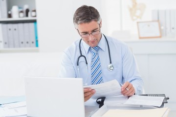 Doctor reading document at table