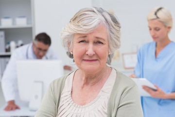 Unhappy patient with doctor and nurse working in background