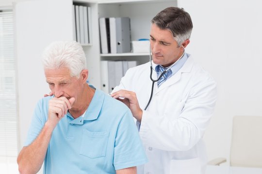 Doctor examining coughing senior patient