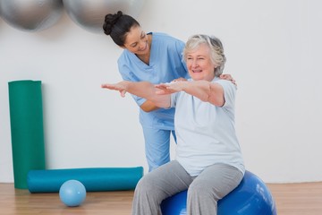 Instructor assisting senior woman in exercising - Powered by Adobe