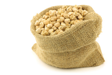 dried chick peas in a burlap bag on a white background