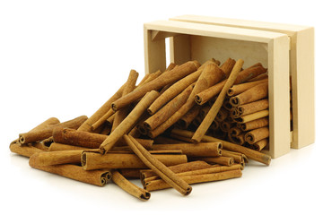 dried cinnamon sticks in a wooden box on a white background