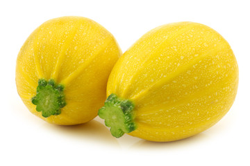 two yellow round zucchini's ( Cucurbita pepo) on a white backgro
