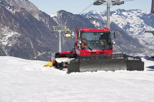 Pistenfahrzeug mit Gondelseilbahn und Bergen