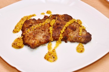 Strip Steak/a piece of strip steak under whole grain mustard