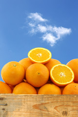 fresh oranges and two halves in a wooden crate