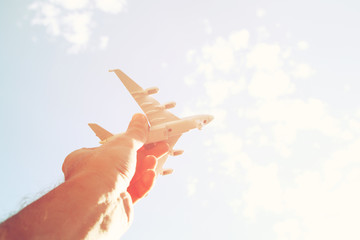 close up photo of man's hand holding toy airplane against blue