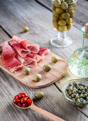 Jamon with capers and olives on the wooden board