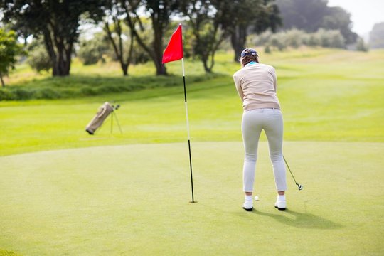 Female Golfer Putting Her Ball