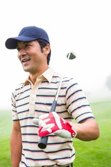 Smiling golfer standing and holding his club