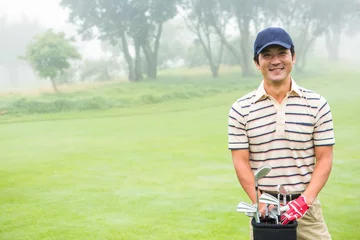 Gordijnen Cheerful golfer smiling at camera holding golf bag © WavebreakMediaMicro