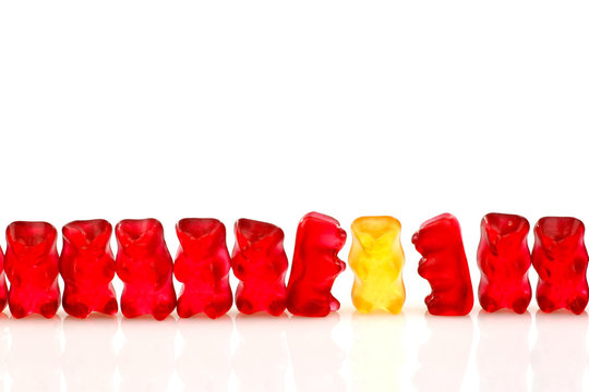 Row Of Red Gummy Bears And A Yellow One Isolated On White