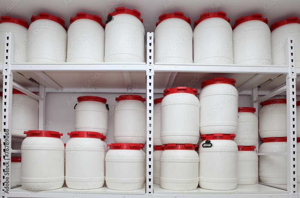 Wall mural white chemical plastic barrels on shelves in storehouse