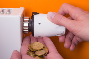 Radiator thermostat, coins  and hand - orange