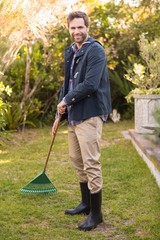 Handsome man raking in his garden