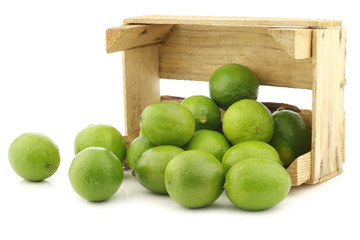 lime fruits in a wooden crate on a white background