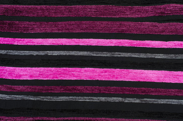 Shades of pink stripes pattern on black velvet fabric background