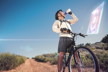 Composite image of fit cyclist drinking water on country terrain