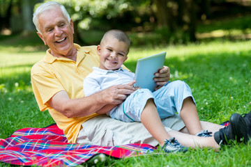 grandfather and child in park using tablet