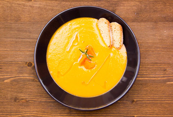 Cream of pumpkin soup with croutons on wooden table top view