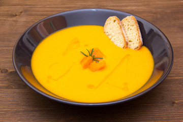 Cream of pumpkin soup with croutons on wooden table