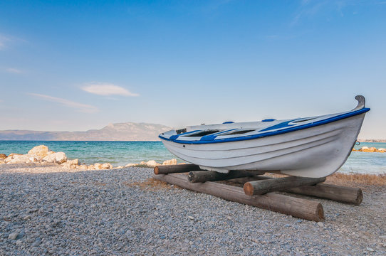 White fishing boat on sand with blue sky and water