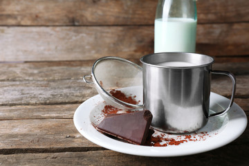 Metal mug and glass bottle of milk with chocolate chunks and