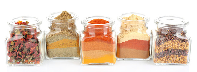 Different kinds of spices in glass bottles isolated on white