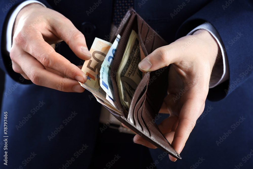 Sticker Leather wallet with money in male hands on dark background