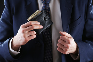 Leather wallet with money in male hands on dark background