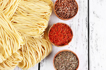 Different dry instant noodles with spices on wooden background