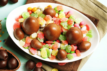 Chocolate Easter eggs on plate, on color wooden background