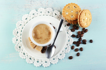 Cup of coffee and tasty cookie on color wooden background
