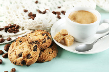 Cup of coffee and tasty cookie on color wooden background