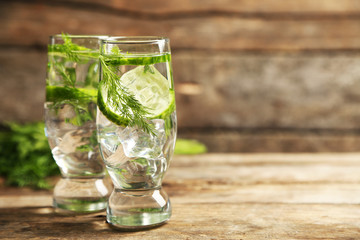 Glasses with fresh organic cucumber water on wooden table