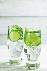 Glasses with fresh organic cucumber water on wooden table