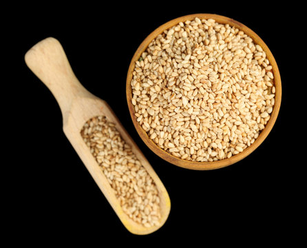 Sesame in wooden bowl, isolated on black