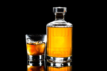 Whiskey on the rocks, with a whiskey bottle in dark background