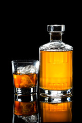 Whiskey on the rocks, with a whiskey bottle in dark background