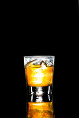 A glass of of Whiskey on the rocks against dark background