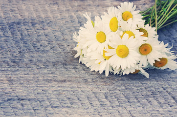 Fototapeta na wymiar Bouquet of daisies on the board in vintage style