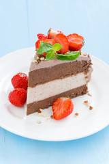 piece of chocolate cake of three layers with fresh strawberries