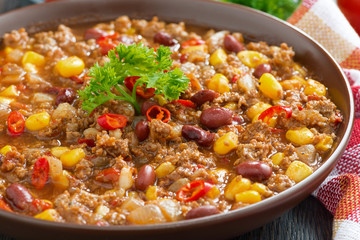 spicy Mexican dish chili con carne in a brown pottery plate