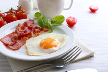 Bacon and eggs on color wooden table background