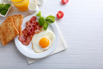 Bacon and eggs on color wooden table background
