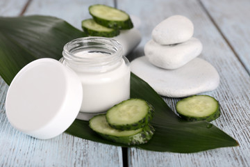 Obraz na płótnie Canvas Cosmetic cream with slices of cucumber and spa stones