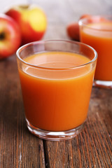 Glasses of juice with apple and carrot on wooden table close up