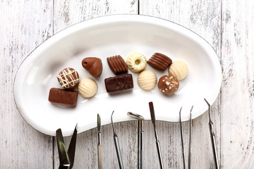 Dentist tools with sweets on tray on wooden background