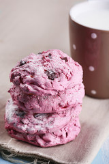 Pink cookies and cup with milk on table close-up