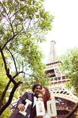 Bride and groom holding I DO letters near Eiffel tower
